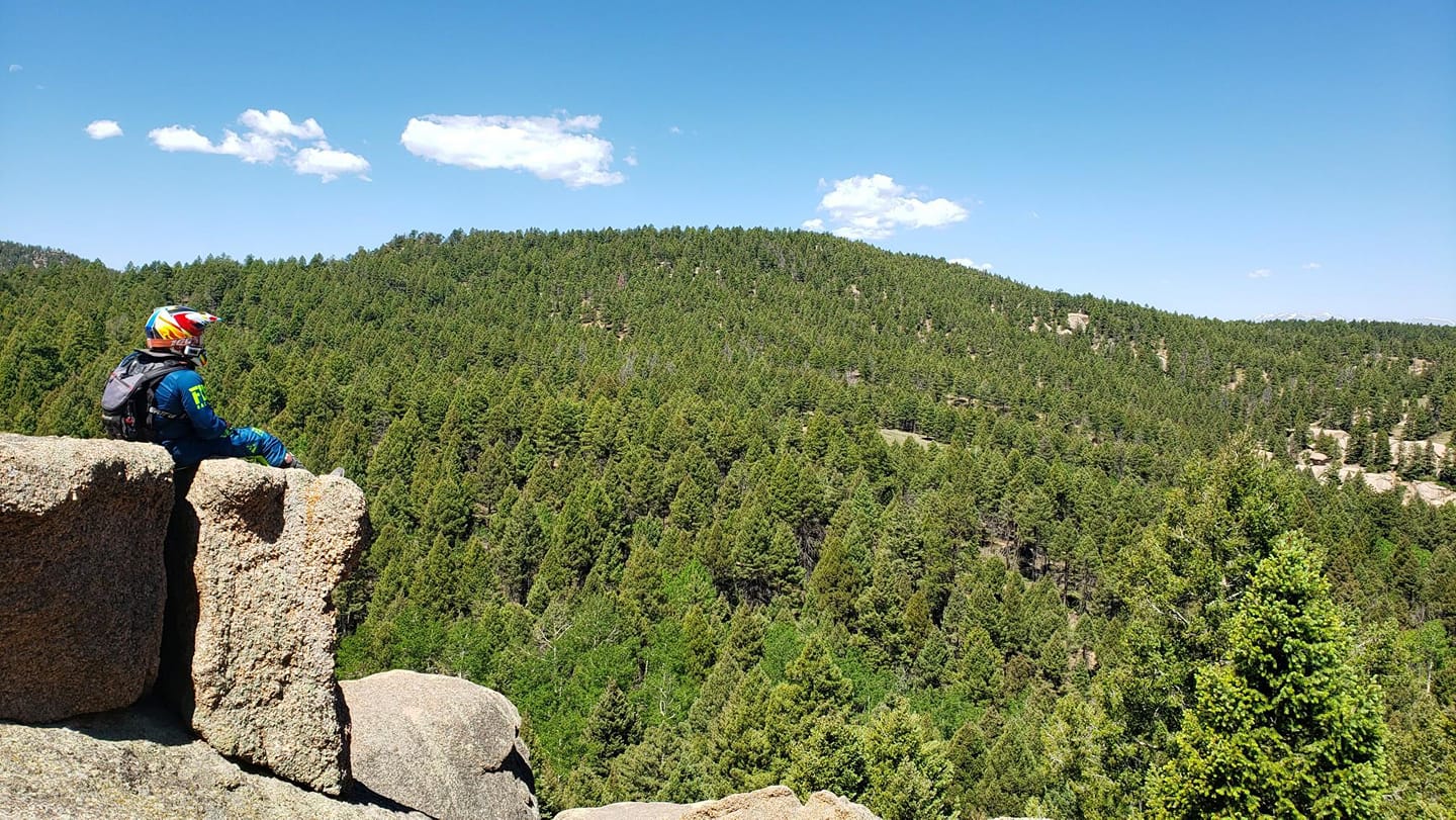 Overlooking a forested valley in motocross gear